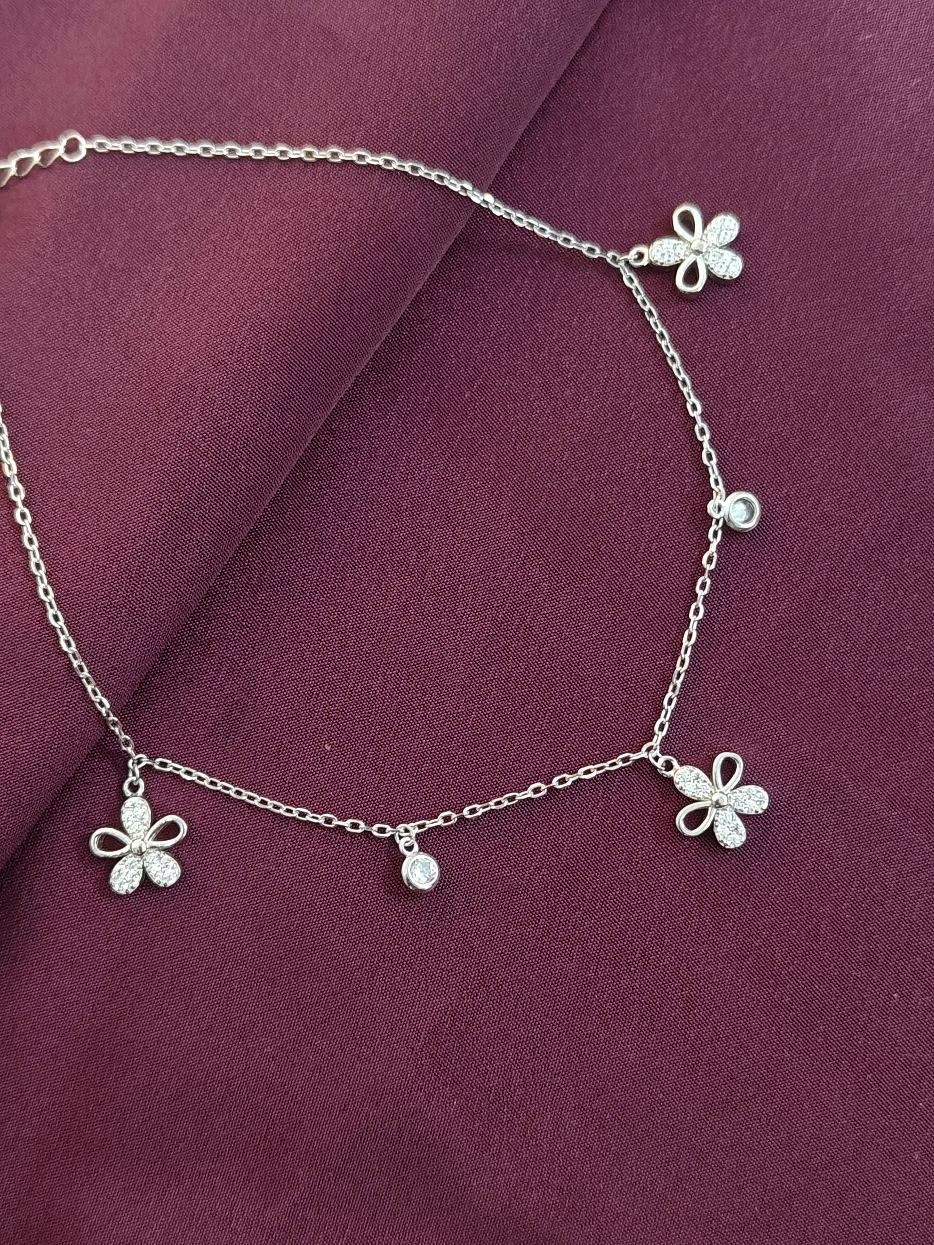 Silver anklet with butterfly charms on a purple fabric background